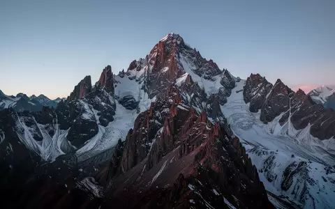 Eine raue, schneebedeckte Bergspitze in den Anden unter einem klaren, kalten Dämmerungshimmel. - Foto: über boerse-global.de