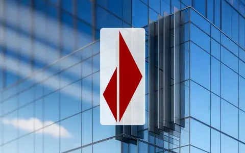 Moderne Glasfassade eines Bankgebäudes bei klarem Himmel als Symbol für Finanzwesen und Marktstabilität. - Foto: über boerse-global.de