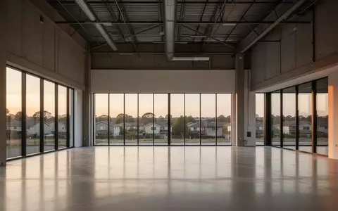 Ein weitläufiger, leerer Innenraum mit hohen Decken und großen Fensterfronten in einer umgenutzten Gewerbeimmobilie. - Foto: über boerse-global.de