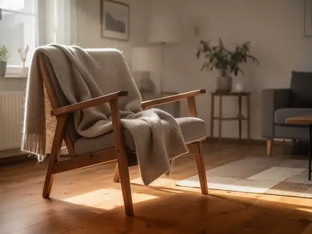 Ein sonnendurchfluteter Wohnraum mit einem Sessel und einer Decke, der eine ruhige und häusliche Atmosphäre vermittelt. - Foto: über boerse-global.de
