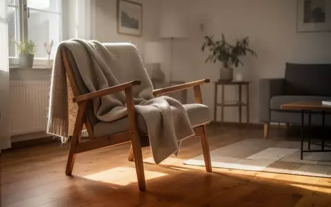 Ein sonnendurchfluteter Wohnraum mit einem Sessel und einer Decke, der eine ruhige und häusliche Atmosphäre vermittelt. - Foto: über boerse-global.de