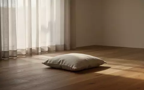 Ein minimalistischer, lichtdurchfluteter Raum mit einem einzelnen Sitzkissen auf einem Holzboden als Symbol für Achtsamkeit. - Foto: über boerse-global.de