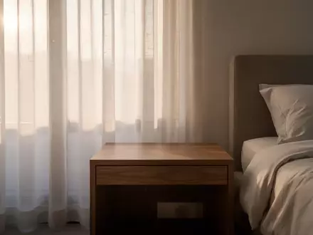 Ein minimalistisches, helles Schlafzimmer bei Tageslicht mit einem leeren Nachttisch. - Foto: über boerse-global.de