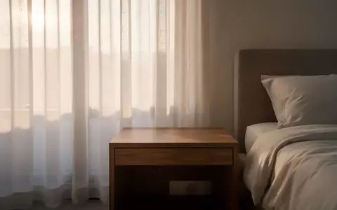 Ein minimalistisches, helles Schlafzimmer bei Tageslicht mit einem leeren Nachttisch. - Foto: über boerse-global.de