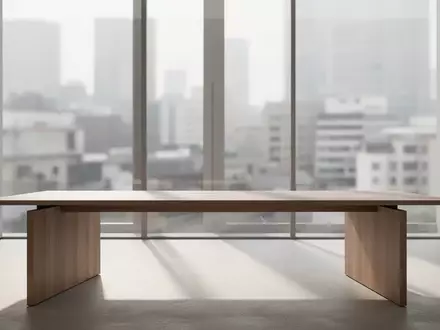 Ein minimalistischer, moderner Arbeitsplatz mit einem leeren Holztisch in einem hellen, architektonisch gestalteten Raum. - Foto: über boerse-global.de