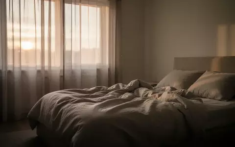 Ein minimalistisch eingerichtetes Schlafzimmer bei Tagesanbruch, das eine ruhige und erholsame Atmosphäre vermittelt. - Foto: über boerse-global.de