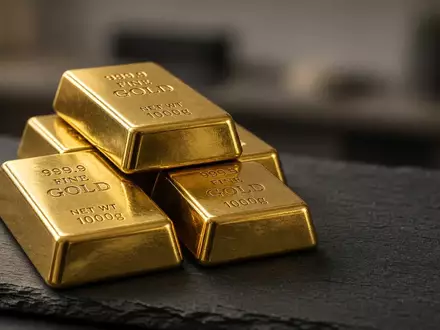 Mehrere Goldbarren auf einer dunklen Schieferplatte bei natürlichem, warmem Licht. - Foto: über boerse-global.de