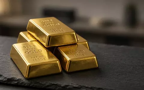Mehrere Goldbarren auf einer dunklen Schieferplatte bei natürlichem, warmem Licht. - Foto: über boerse-global.de