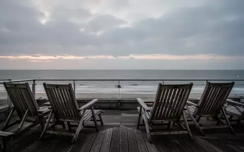 Leere Hotelterrasse mit Blick auf die Nordsee bei Dämmerung unter bewölktem Himmel. - Foto: über boerse-global.de