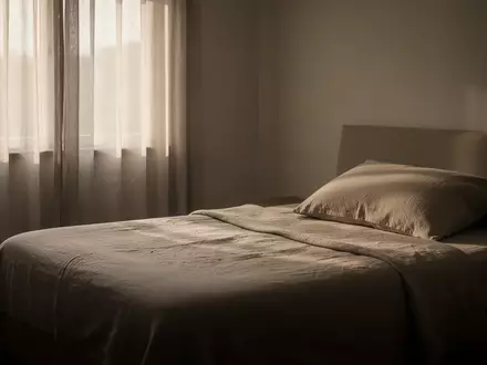 Ein schlichtes, ruhig wirkendes Schlafzimmer bei morgendlichem Licht mit einem unbenutzten, ordentlich gemachten Bett. - Foto: ĂĽber boerse-global.de