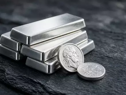 Polierte Silberbarren und Münzen auf einer dunklen Schieferplatte bei natürlichem Licht. - Foto: über boerse-global.de