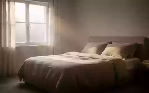 Ein minimalistisch eingerichtetes Schlafzimmer am frühen Morgen, in dem sanftes Tageslicht auf ein gemachtes Bett fällt. - Foto: über boerse-global.de