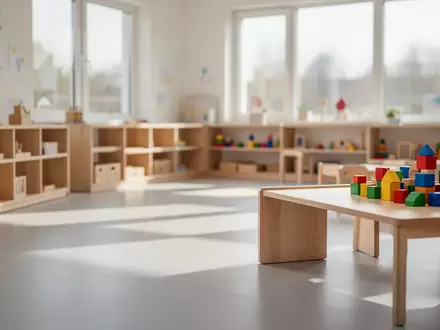 Ein heller, moderner Gruppenraum in einer Kindertagesstätte mit schlichten Holzmöbeln und einfallendem Tageslicht. - Foto: über boerse-global.de