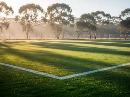 Ein sonnendurchflutetes Fußballfeld mit frisch gemähtem Rasen und weißen Spielfeldmarkierungen in einer australischen Landschaft. - Foto: über boerse-global.de