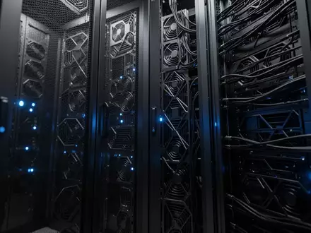 Dunkler Serverraum mit metallischen Hardware-Racks und dezenten blauen LED-Lichtern in einer industriellen Umgebung. - Foto: über boerse-global.de