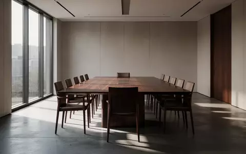 Ein minimalistischer, leerer Konferenzraum mit einem großen Holztisch und natürlichem Lichteinfall. - Foto: über boerse-global.de