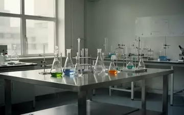 Ein minimalistisches, helles Labor mit Edelstahltisch und wissenschaftlichen Glasgeräten bei natürlichem Tageslicht. - Foto: über boerse-global.de