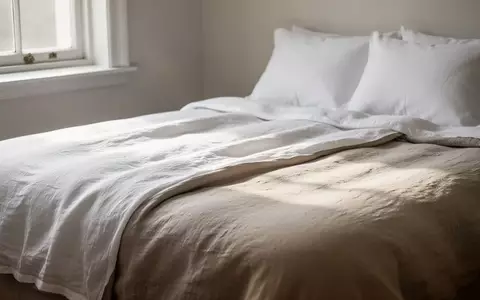 Ein ordentlich gemachtes Bett in einem hellen, minimalistischen Schlafzimmer mit Fokus auf die Textur der Bettwäsche. - Foto: über boerse-global.de