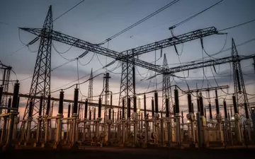 Ein Hochspannungsumspannwerk mit stählernen Gittermasten vor einem dämmrigen Abendhimmel. - Foto: über boerse-global.de