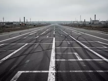 Eine leere, asphaltierte Teststrecke mit verblassten Fahrbahnmarkierungen auf einem weitläufigen, industriellen Gelände. - Foto: über boerse-global.de