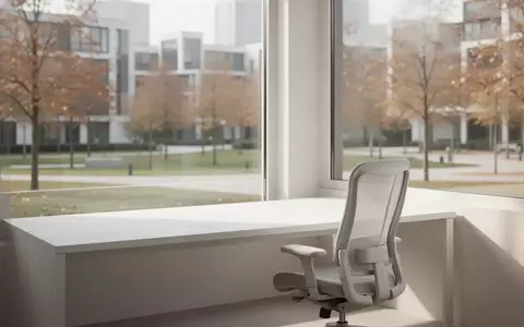 Ein minimalistischer, sonnendurchfluteter Arbeitsbereich mit einem leeren Schreibtisch vor einem Fenster mit Parkblick. - Foto: über boerse-global.de