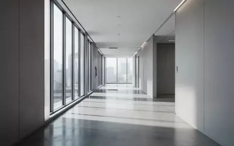 Ein minimalistischer, moderner Büroflur mit poliertem Betonboden und hellem Tageslicht, das durch hohe Fenster fällt. - Foto: über boerse-global.de