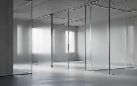 Ein minimalistischer, moderner Innenraum mit klaren geometrischen Linien und diffusem Tageslicht hinter Glaswänden. - Foto: über boerse-global.de