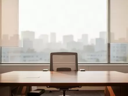 Ein minimalistischer Arbeitsbereich mit einem leeren Schreibtisch und einem Fenster mit Blick auf eine städtische Skyline. - Foto: über boerse-global.de