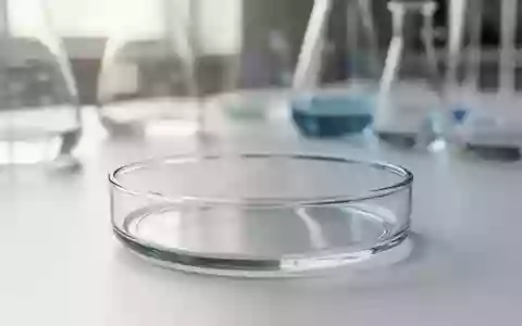 Ein steriler Labortisch mit einer Glasschale vor einem unscharfen Hintergrund aus wissenschaftlichen Geräten. - Foto: über boerse-global.de