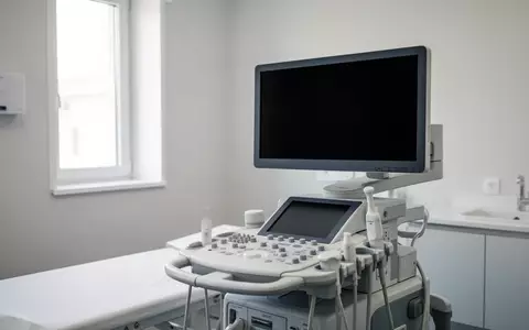 Ein modernes, steriles Untersuchungszimmer in einer Klinik mit einem medizinischen Ultraschallgerät und dunklem Bildschirm. - Foto: über boerse-global.de