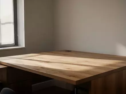Ein minimalistischer, heller Arbeitsplatz mit Holztisch in einem ruhigen Raum bei natürlichem Tageslicht. - Foto: über boerse-global.de