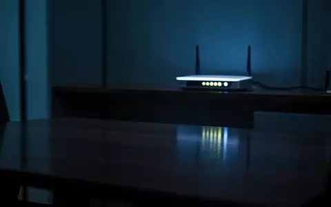 Ein schummrig beleuchteter, moderner Büroraum bei Nacht mit kühlem Licht und einem einzelnen, leuchtenden Netzwerk-Router. - Foto: über boerse-global.de