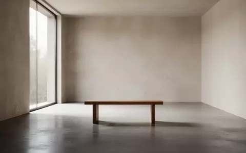 Ein minimalistischer, ruhiger Raum mit einer Holzbank vor einem großen Fenster, das sanftes Tageslicht hereinlässt. - Foto: über boerse-global.de