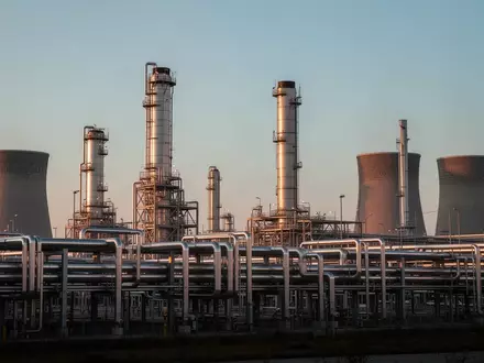 Weitläufiges Industriegelände mit Rohrleitungen und Kühltürmen eines Chemieparks bei Dämmerung. - Foto: über boerse-global.de