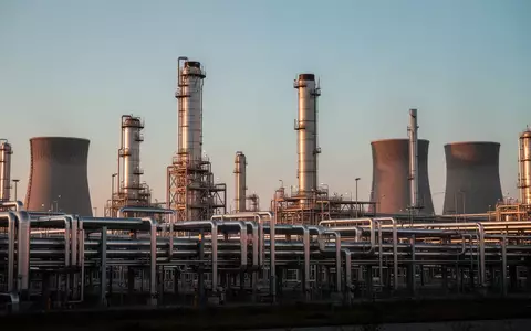 Weitläufiges Industriegelände mit Rohrleitungen und Kühltürmen eines Chemieparks bei Dämmerung. - Foto: über boerse-global.de