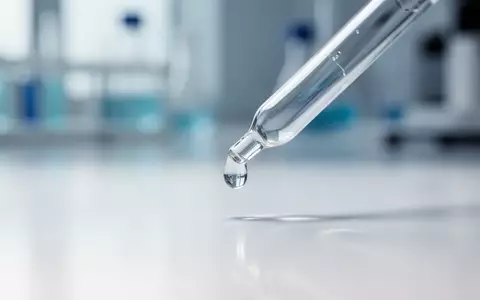 Eine Nahaufnahme einer Pipette mit einem Wassertropfen in einem sterilen, minimalistischen Laborumfeld. - Foto: über boerse-global.de