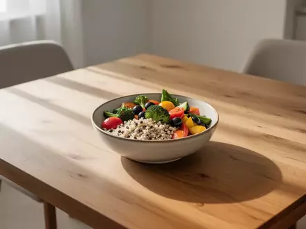Ein minimalistisch gedeckter Holztisch mit einer Schale frischem Gemüse und Vollkornprodukten in hellem Tageslicht. - Foto: über boerse-global.de