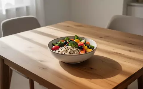 Ein minimalistisch gedeckter Holztisch mit einer Schale frischem Gemüse und Vollkornprodukten in hellem Tageslicht. - Foto: über boerse-global.de