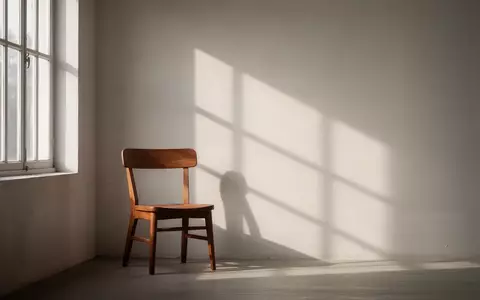 Ein ruhiger, sonnendurchfluteter Raum mit einem leeren Holzstuhl vor einem Fenster, der eine Atmosphäre von Stille und innerer Balance vermittelt. - Foto: über boerse-global.de