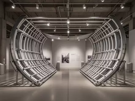 Eine hufeisenförmige, industrielle Metallkonstruktion aus Stahl und Aluminium in einem minimalistischen Museumsraum. - Foto: über boerse-global.de