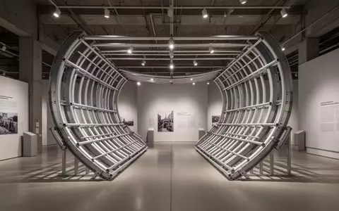 Eine hufeisenförmige, industrielle Metallkonstruktion aus Stahl und Aluminium in einem minimalistischen Museumsraum. - Foto: über boerse-global.de