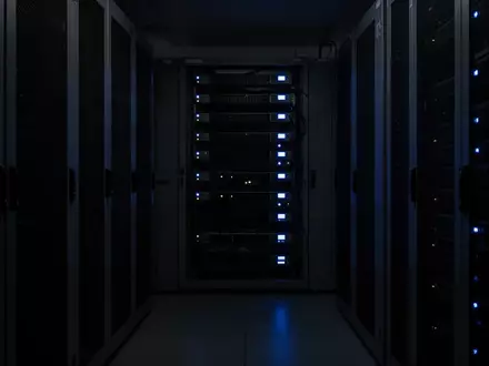 Dunkler, minimalistischer Serverraum mit schwach leuchtenden blauen Status-LEDs an Hardware-Racks. - Foto: über boerse-global.de