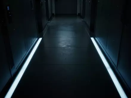 Ein dunkler, minimalistischer Flur mit einer einzelnen, kalt blauen Lichtleiste, die eine Atmosphäre der digitalen Bedrohung erzeugt. - Foto: über boerse-global.de