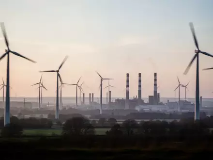 Industrielandschaft mit Windkraftanlagen und Fabrikschornsteinen bei Morgendämmerung in Deutschland. - Foto: über boerse-global.de
