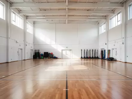 Leere, helle Sporthalle mit poliertem Holzboden und einfallendem Tageslicht. - Foto: über boerse-global.de