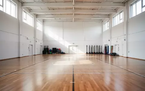 Leere, helle Sporthalle mit poliertem Holzboden und einfallendem Tageslicht. - Foto: über boerse-global.de