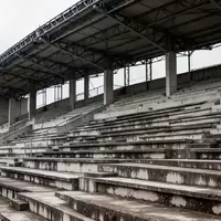 Leere, graue Betontribünen eines Stadions mit einer symmetrischen Anordnung von Sitzreihen und Stahlträgern. - Foto: über boerse-global.de