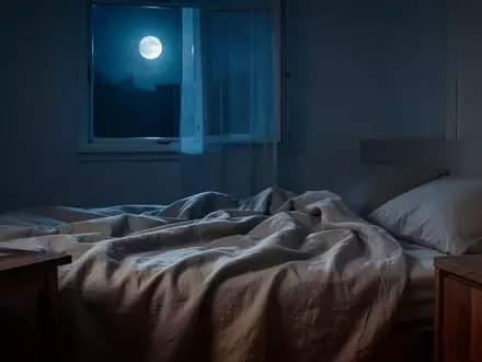 Ein minimalistisches, ruhiges Schlafzimmer bei Nacht mit sanftem Mondlicht, das auf ein ungemachtes Bett fällt. - Foto: über boerse-global.de