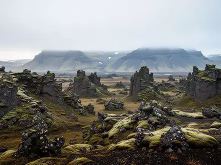 Eine weitläufige, moosbewachsene isländische Vulkanlandschaft mit nebligen Bergen im Hintergrund bei sanftem Tageslicht. - Foto: über boerse-global.de