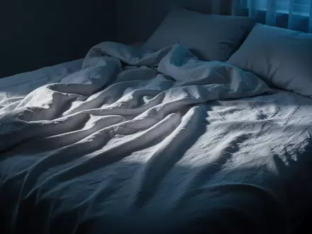 Ein ungemachtes Bett mit zerknitterten weißen Leinentüchern in einem ruhig beleuchteten Schlafzimmer bei Morgendämmerung. - Foto: über boerse-global.de
